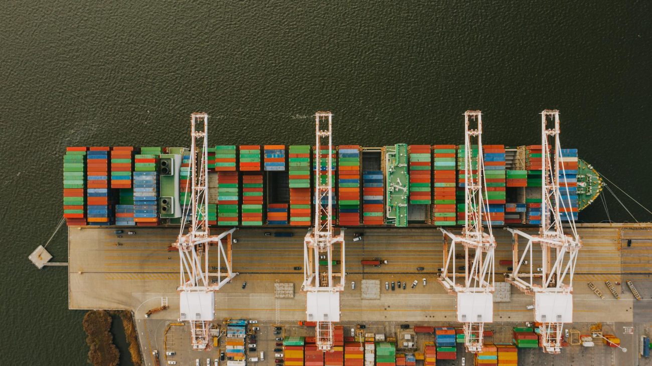 Container ship alongside port cranes with stacked containers