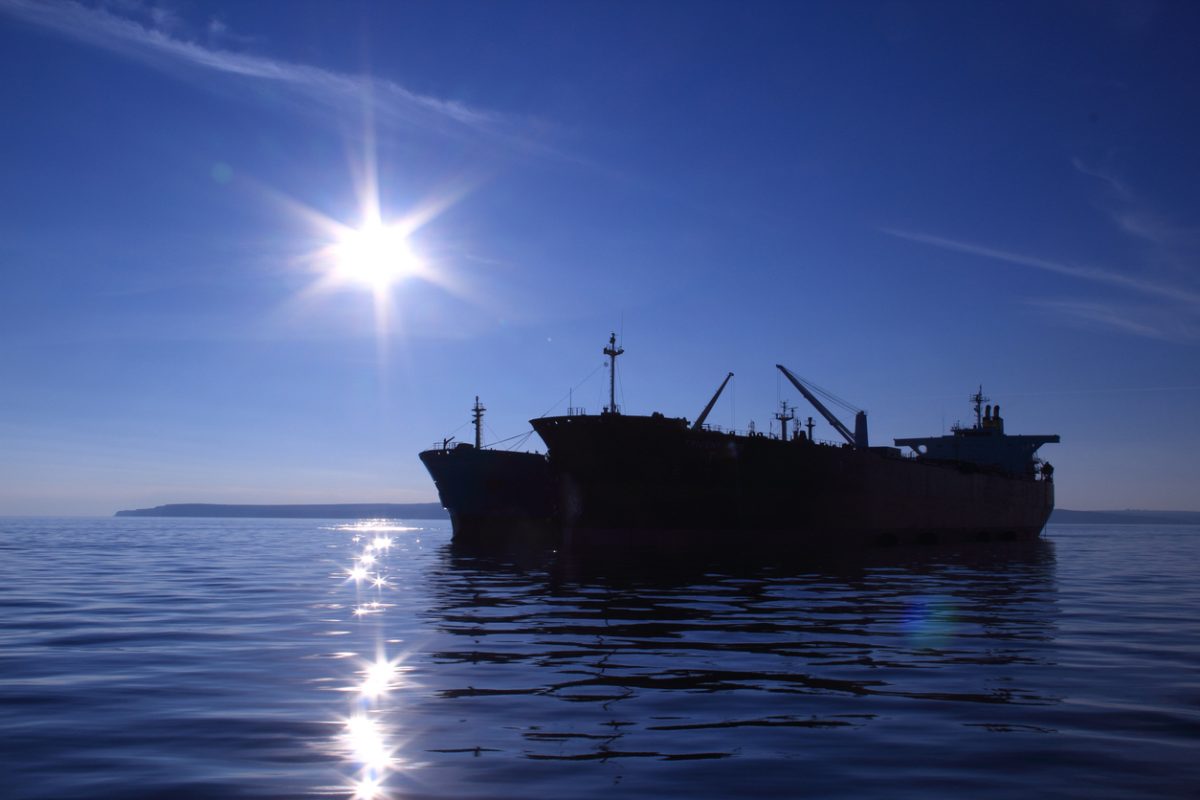 Oil tankers anchored offshore illustrating global crude shipping and sanctions enforcement risk