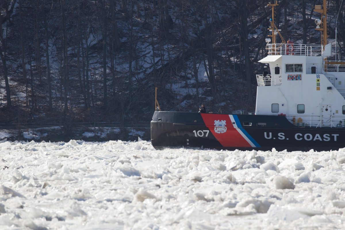 Icebreaker ship cutting through ice on a frozen sea under clear sky