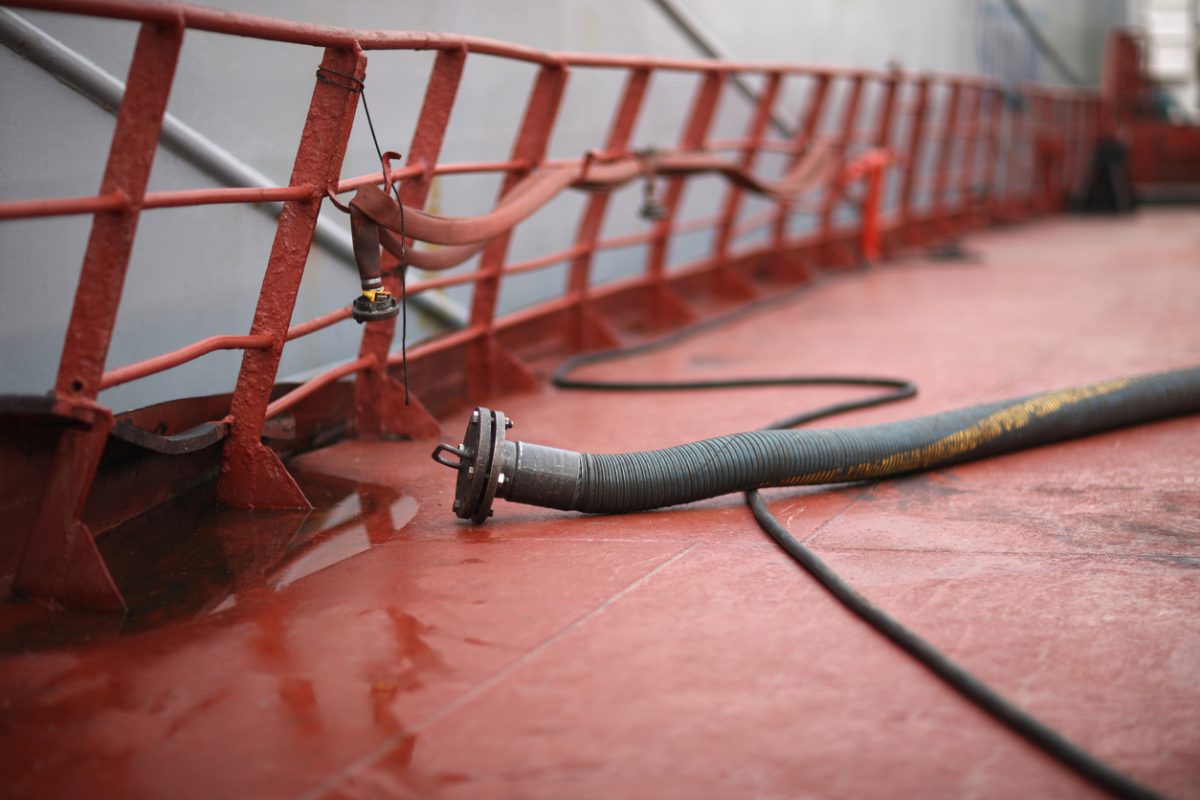 Crude oil tanker deck with pipelines and hoses for marine fuel transfer operations