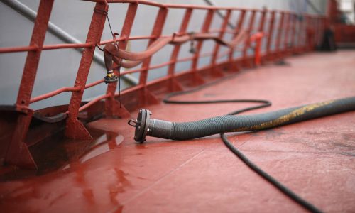 Crude oil tanker deck with pipelines and hoses for marine fuel transfer operations