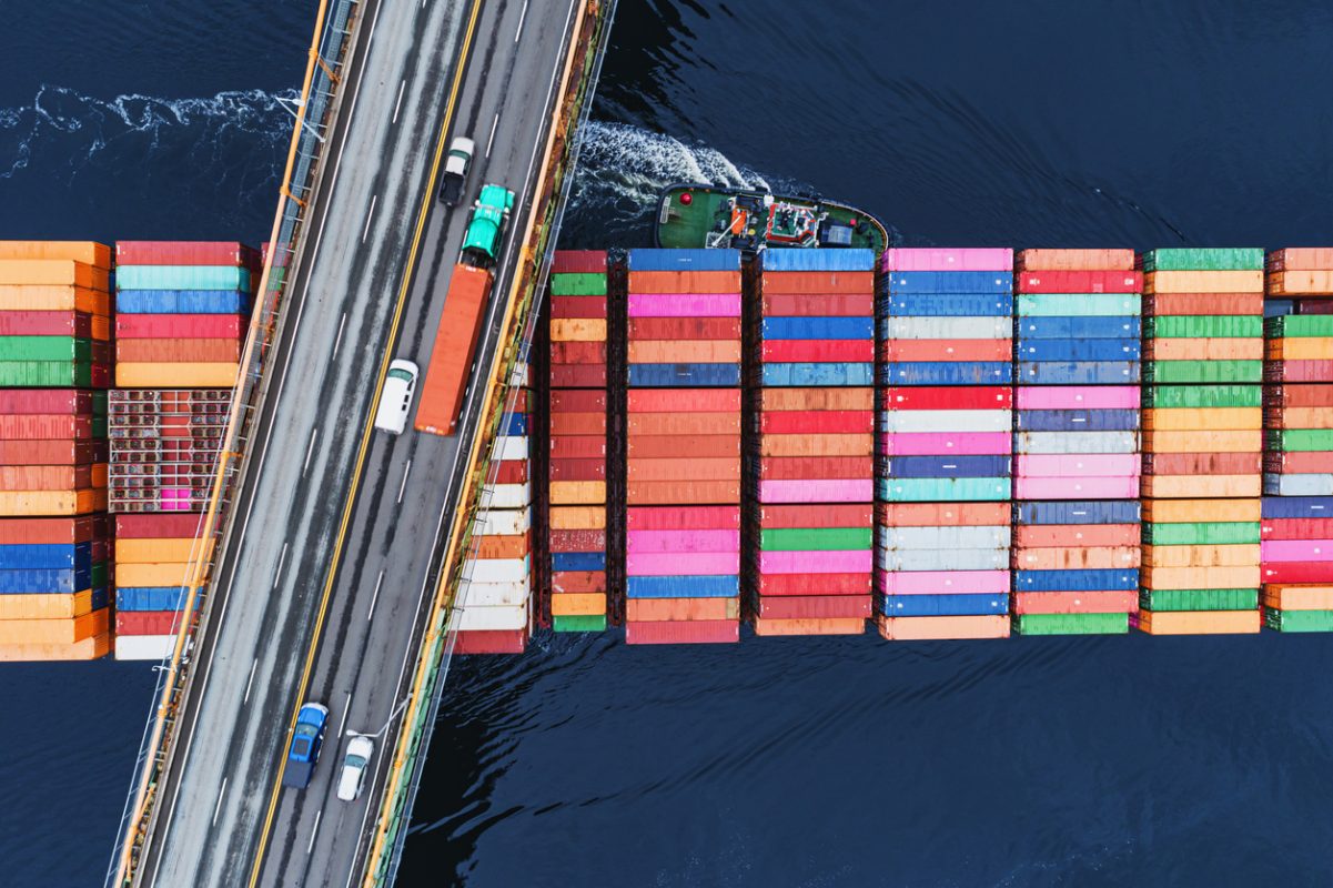 Container ship departing port carrying cargo on global maritime trade routes