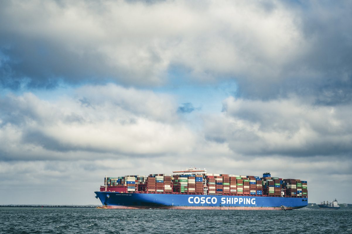 COSCO container ship departing the Port of Rotterdam carrying stacked shipping containers