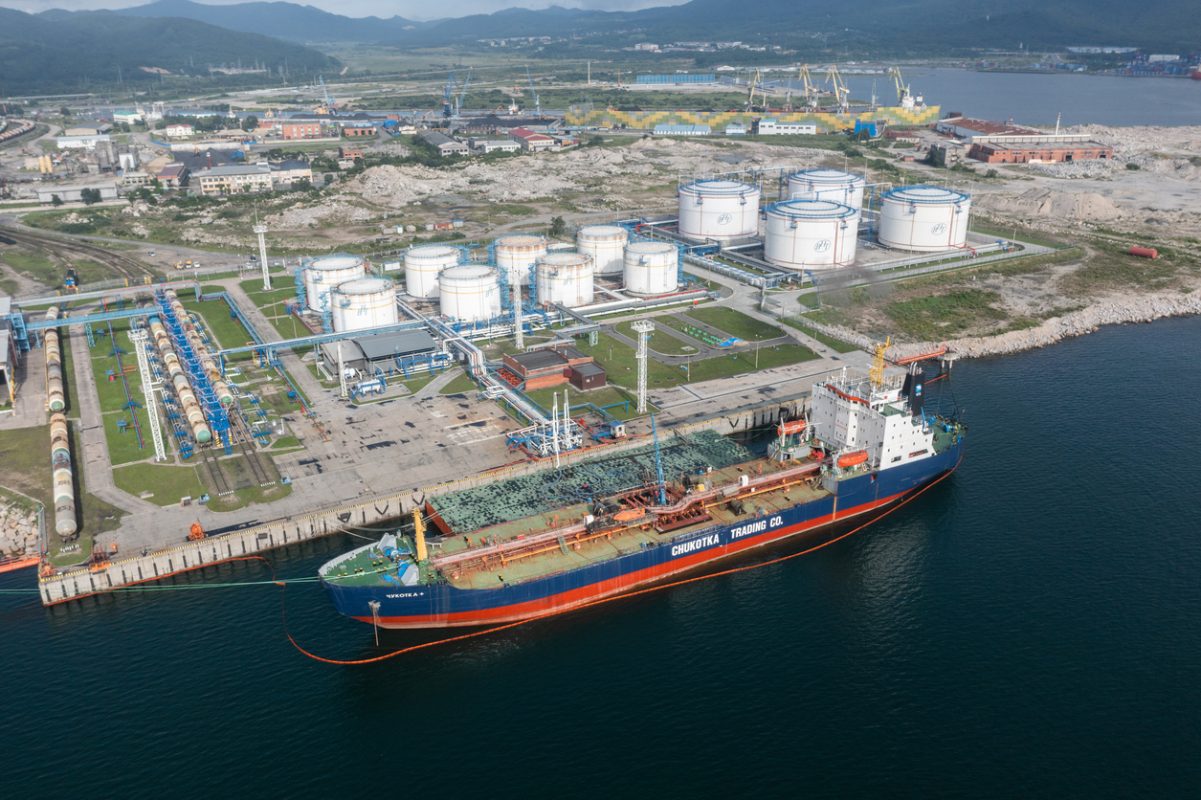 Oil tanker moored beside storage tanks at petroleum export terminal.