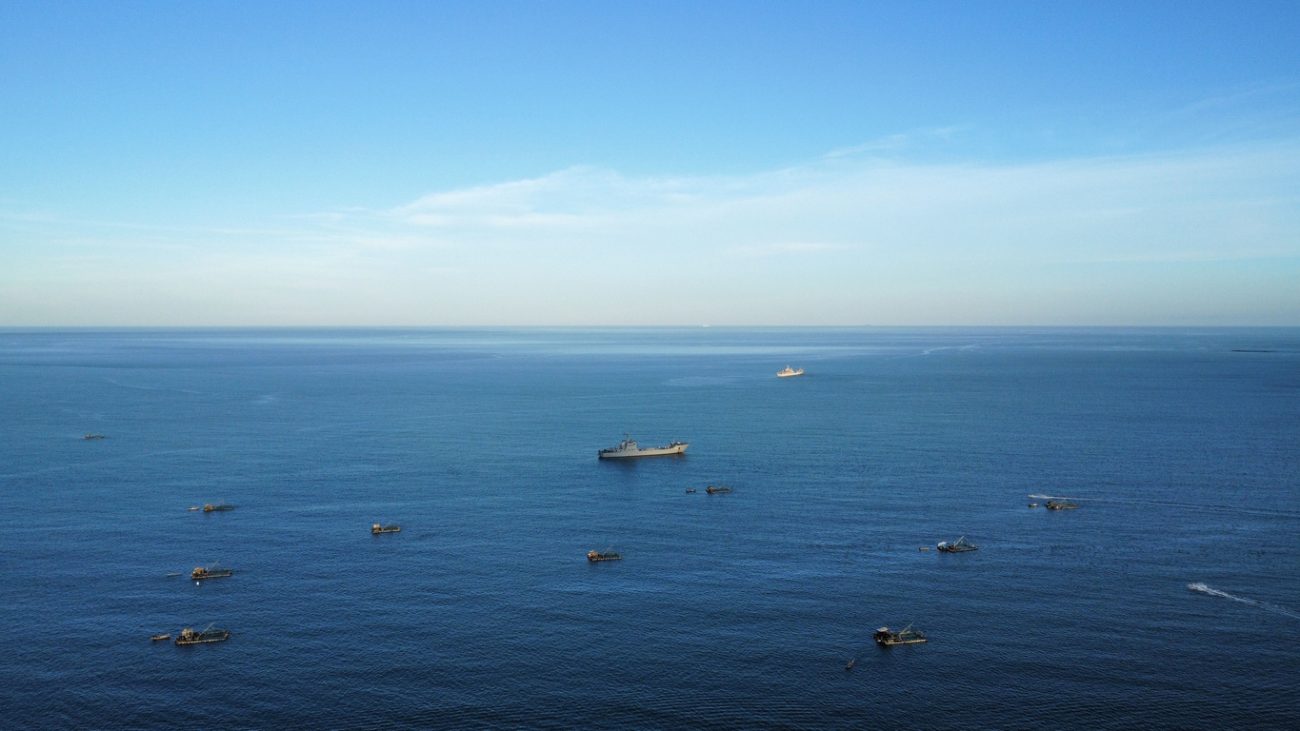 Ship and small boats at sea representing global shipping routes affected by maritime security concerns