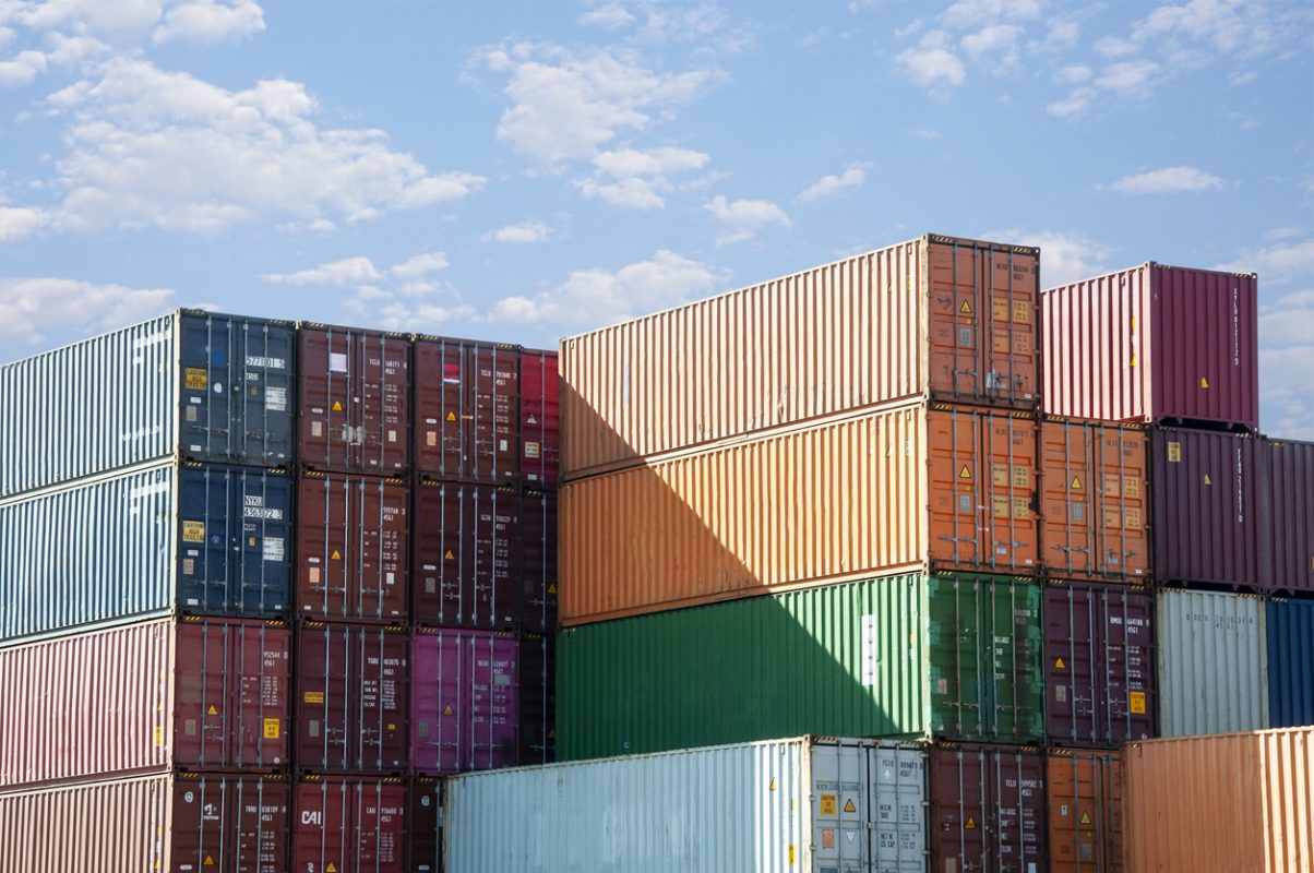 Stacked container shipping boxes at a port terminal representing global container trade and maritime logistics