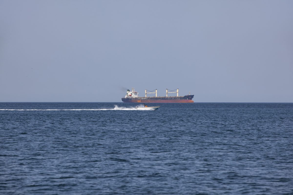 Cargo ship and speedboat in the Strait of Hormuz, a key shipping route for global oil and tanker traffic.