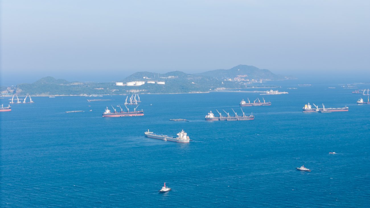 Cargo ships and oil tankers anchored at sea representing delays in global shipping routes