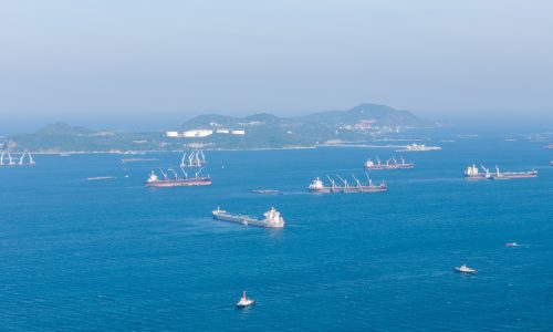 Cargo ships and oil tankers anchored at sea representing delays in global shipping routes