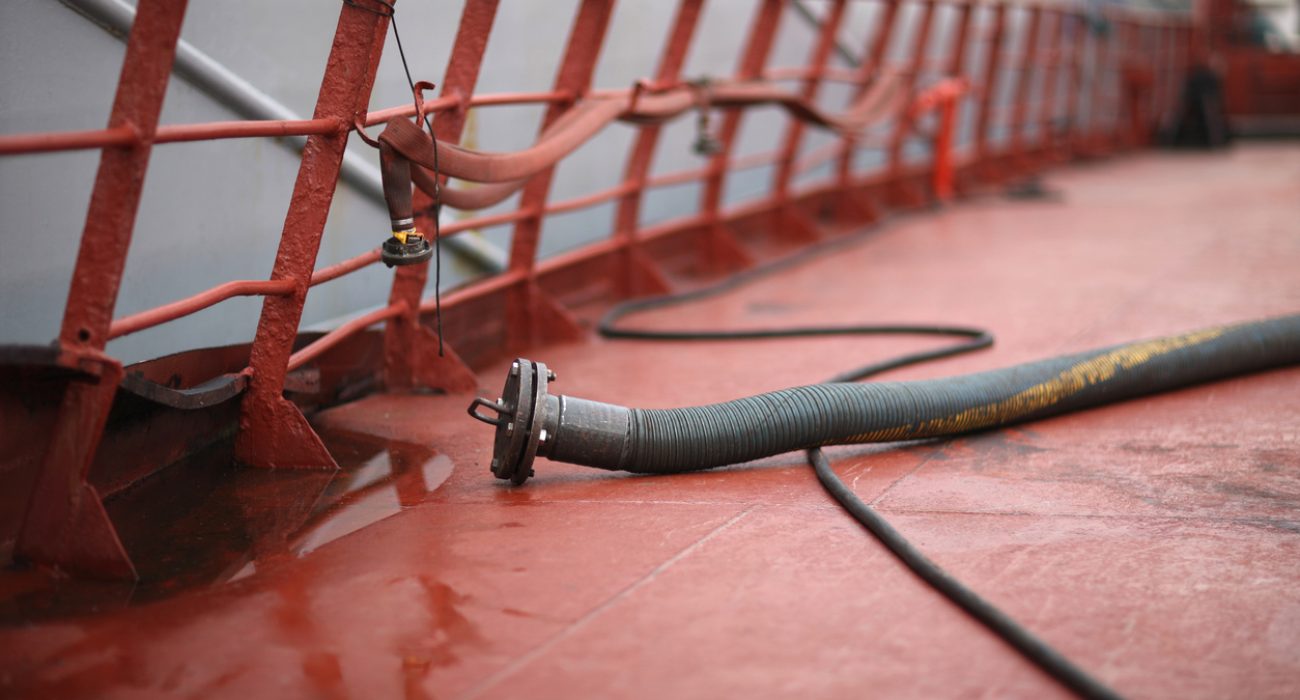 Crude oil tanker deck with pipelines and hoses for marine fuel transfer operations
