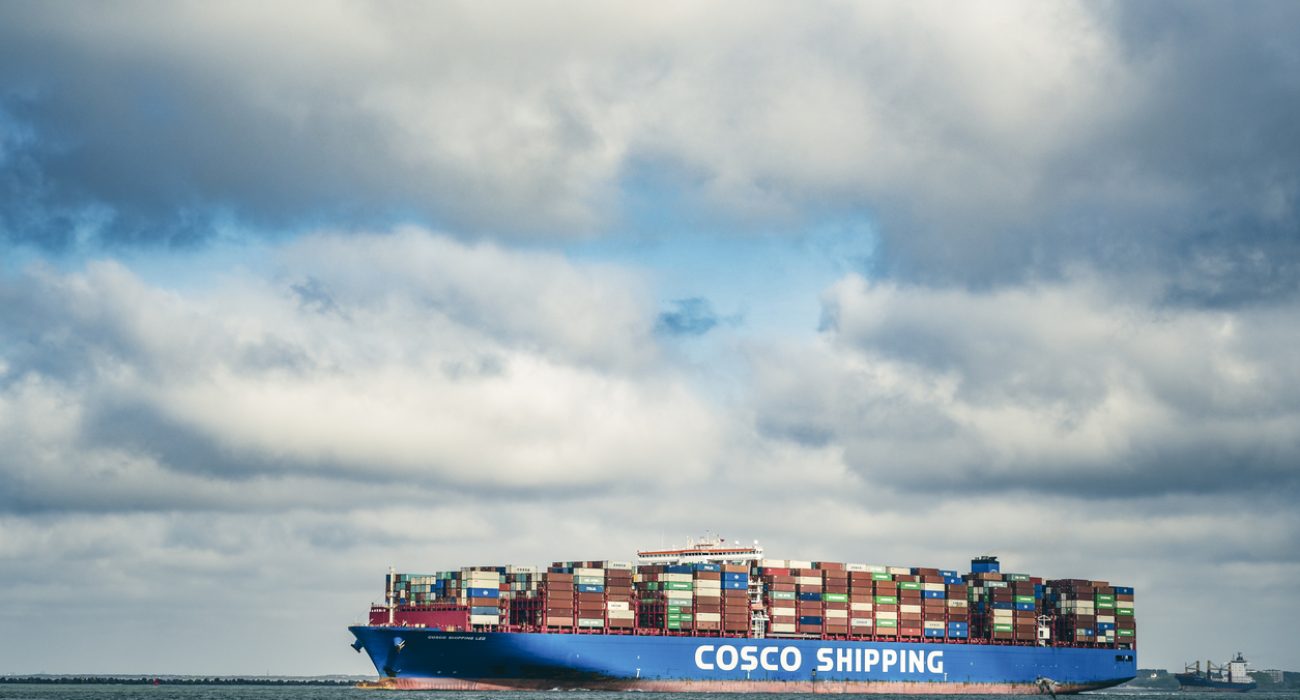 COSCO container ship departing the Port of Rotterdam carrying stacked shipping containers