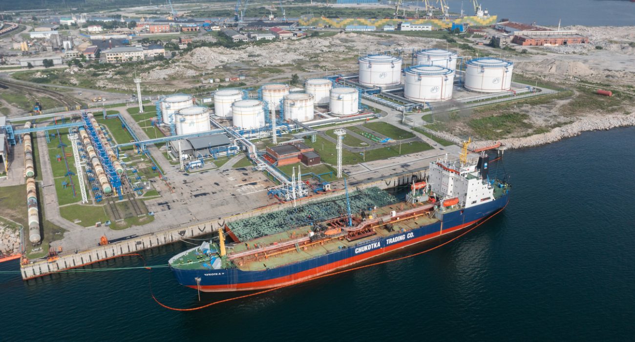 Oil tanker moored beside storage tanks at petroleum export terminal.