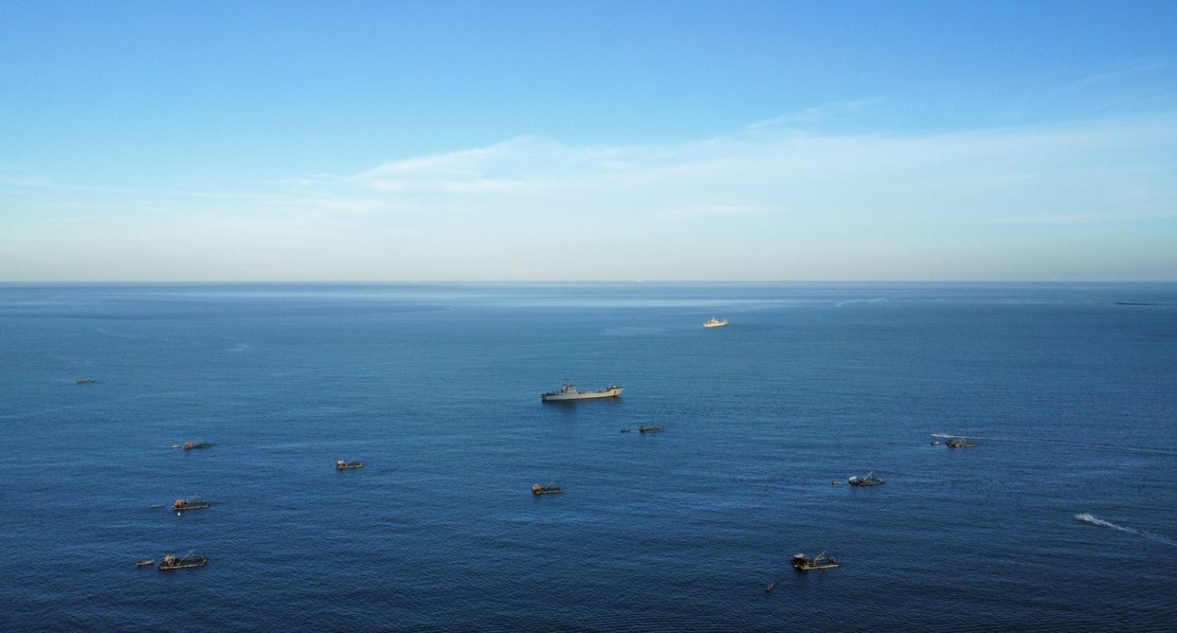 Ship and small boats at sea representing global shipping routes affected by maritime security concerns
