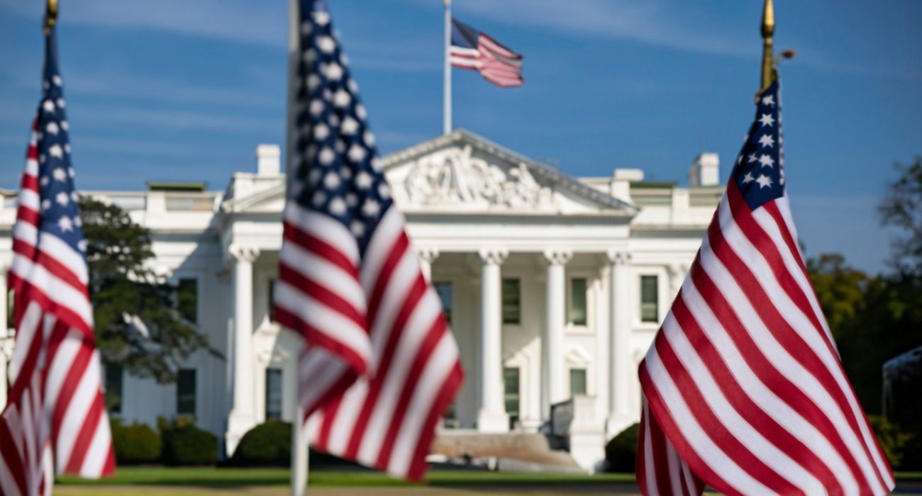 US flags and the White House in Washington linked to Jones Act waiver allowing foreign ships in domestic trade