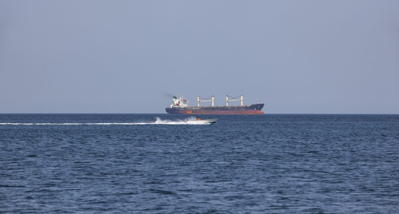 Cargo ship and speedboat in the Strait of Hormuz, a key shipping route for global oil and tanker traffic.