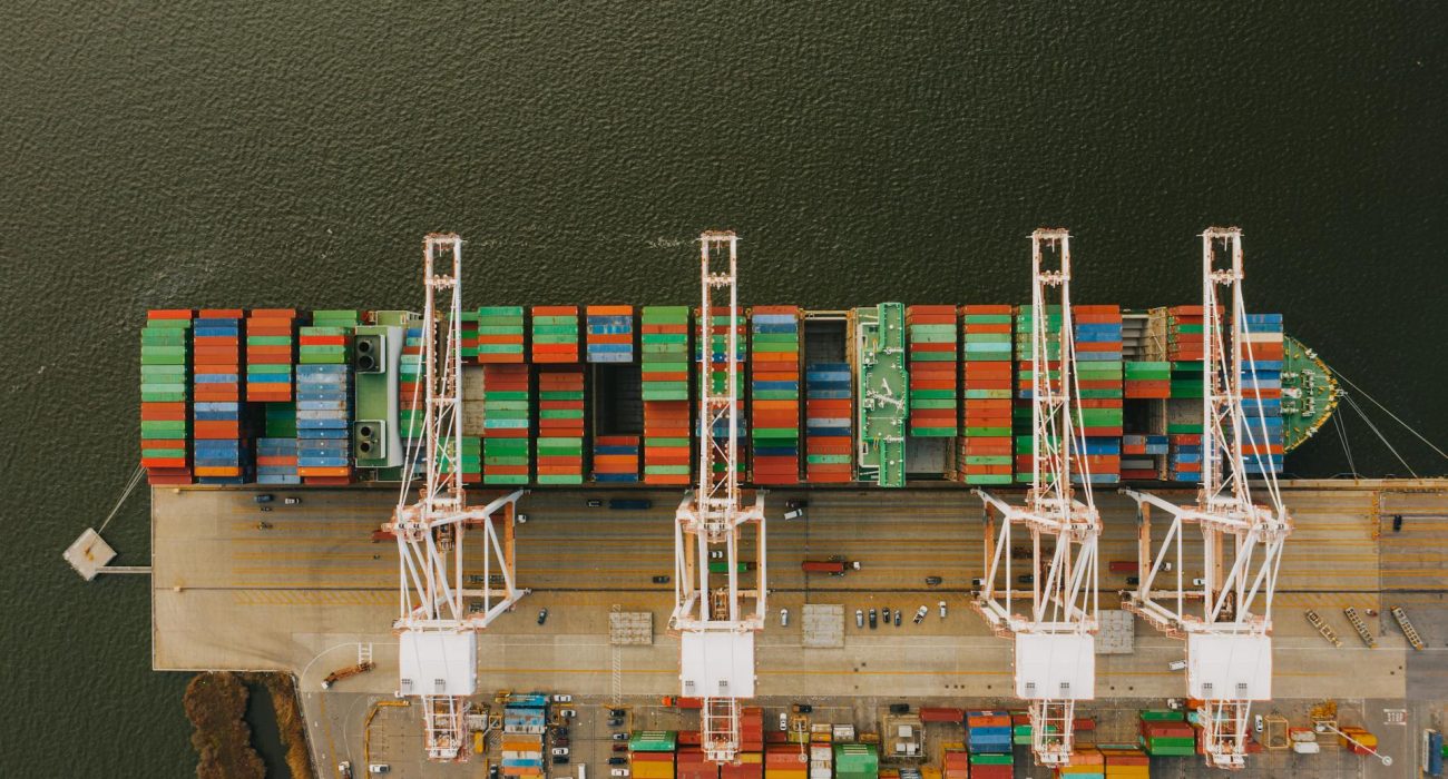 Container ship alongside port cranes with stacked containers