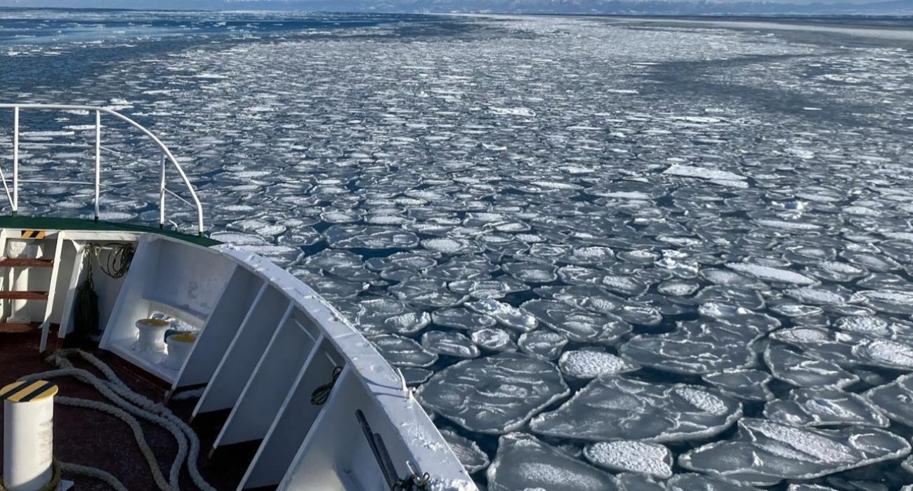 Vessel moving through broken ice on a frozen waterway during winter navigation conditions.