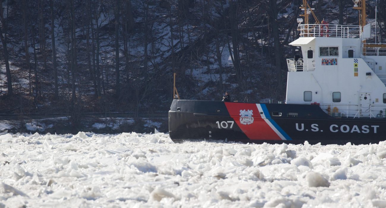 Icebreaker ship cutting through ice on a frozen sea under clear sky